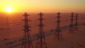 Aerial view of electrical transmission tower grid system spanning across desert landscape at sunset, showing interconnected power lines and substations, high voltage infrastructure, professional utility operations setting