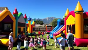 Professional event setup with colorful bounce houses in sunny Colorado backyard, happy families gathered around, mountains visible in background, clear blue sky, vibrant atmosphere
